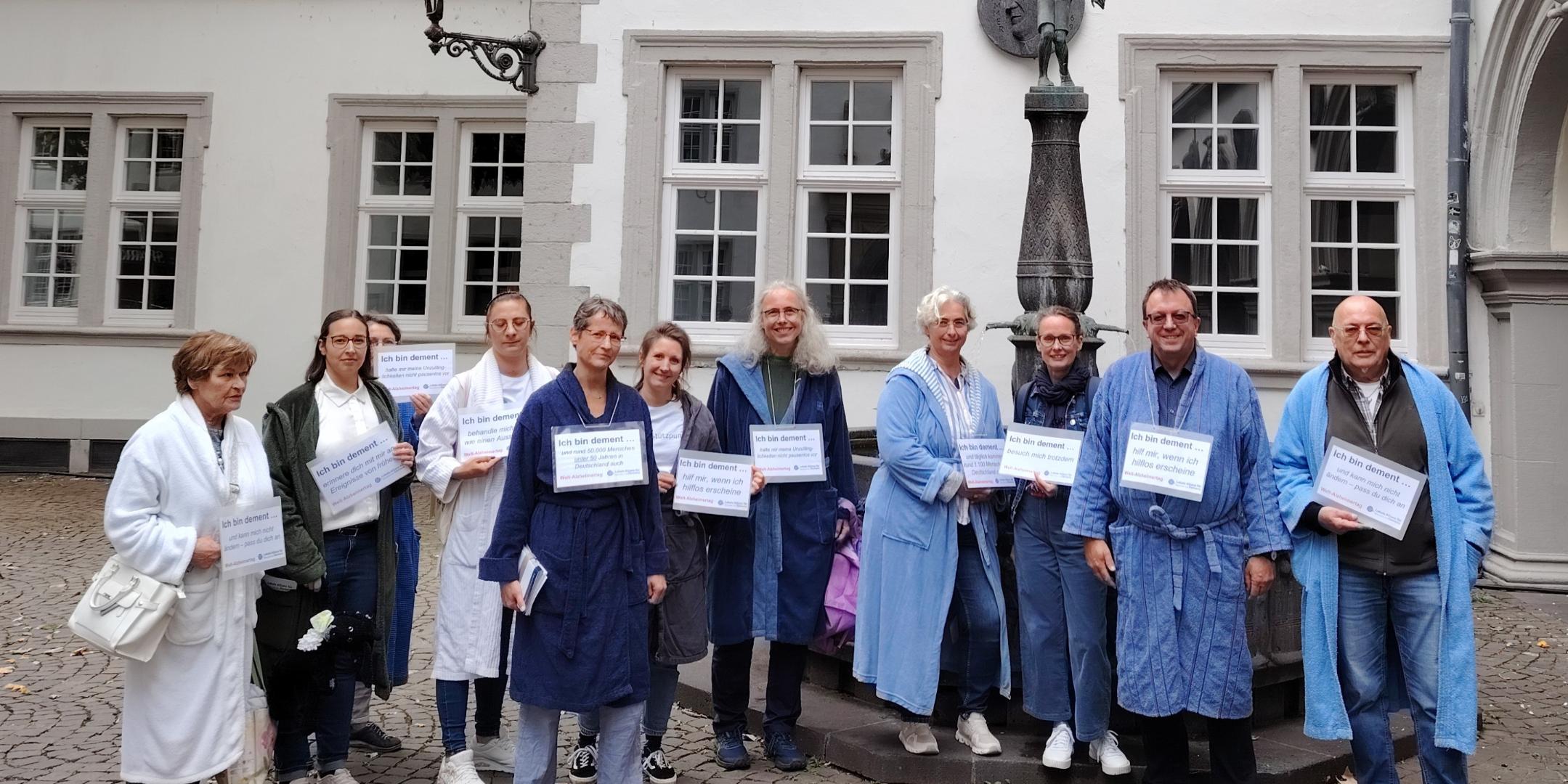 Eine Gruppe aus Personen im Bademantel in Koblenz, die mit Schildern auf Demenz aufmerksam machen