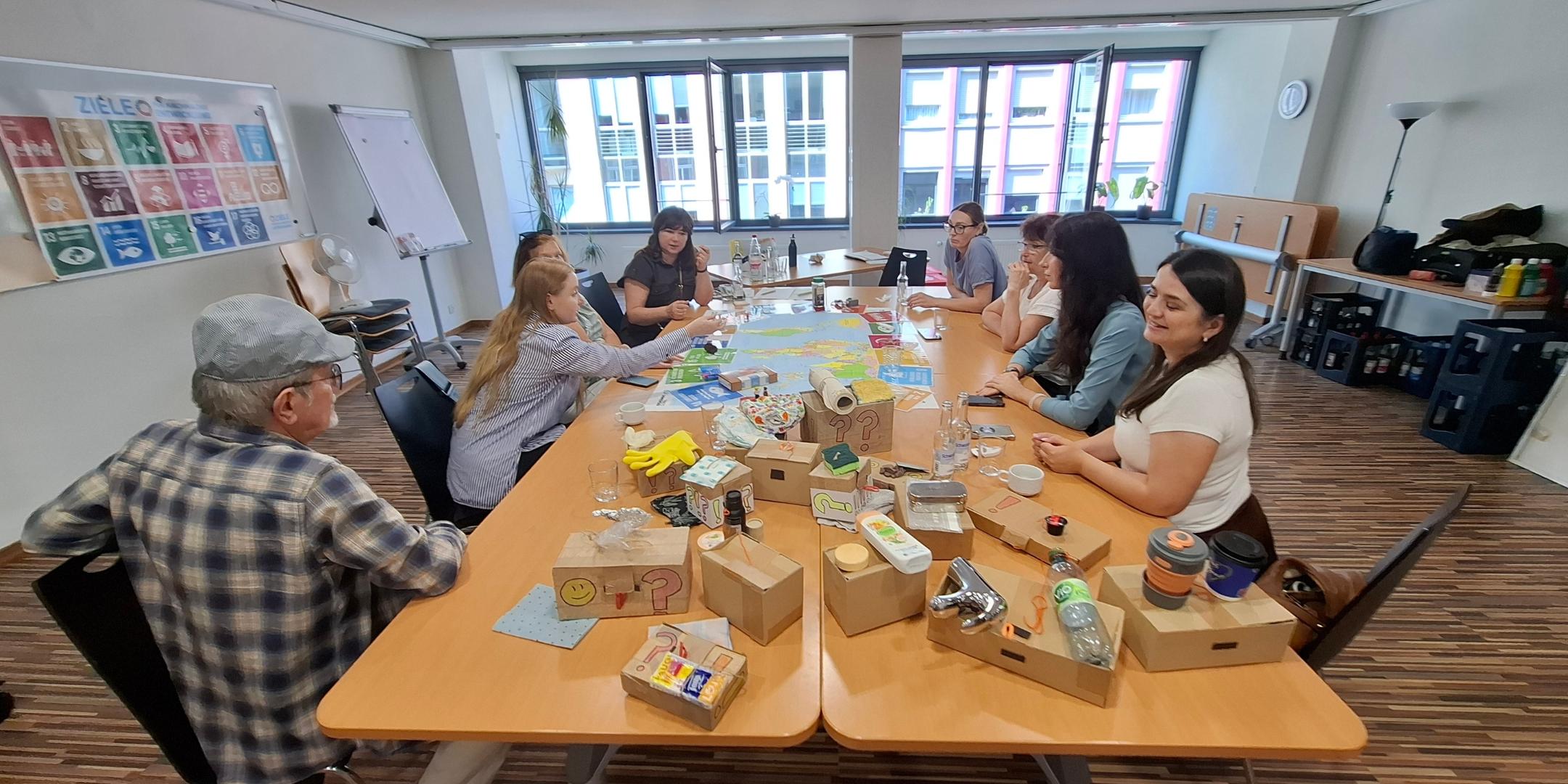 Eine Gruppe von Menschen sitzt um einen Tisch herum, auf dem Materialien zum Thema Nachhaltigkeit liegen (c) Kirsten Dembowski Eine Gruppe von Menschen sitzt um einen Tisch herum, auf dem Materialien zum Thema Nachhaltigkeit liegen